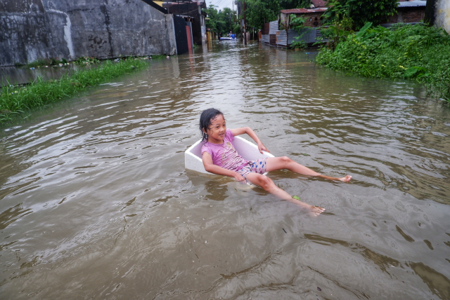 Seorang anak bermain di tengah  banjir di Blok 10, Perumnas Antang, Makassar, Makassar, Minggu (22/12/2024).