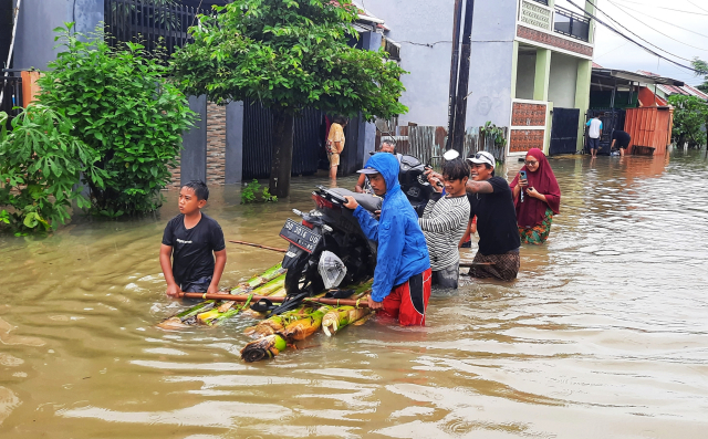 Warga mengevakuasi kendaraan  menggunakan rakit di Blok 10 Perumnas Antang, Makassar.