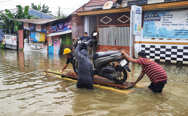 Warga mengevakuasi kendaraan  menggunakan rakit di Blok 10 Perumnas Antang, Makassar.