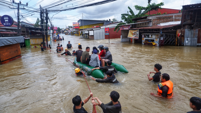 Tim SAR dari Mapala STIBA Makassar membantu warga melewati arus banjir di Jalan Nipa-nipa, Kecamatan Manggala, Makassar.