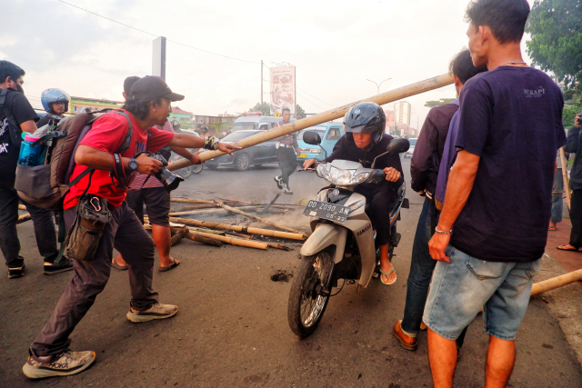 Seorang pewarta foto membantu pengendara melintas di tengah blokade jalan depan kampus Unibos.