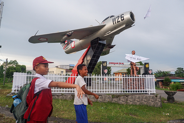 Dua anak tampak asyik bermian pesawat kertas di depan monumen Pesawat TNI AU MiG-17 Fresco, Simpang Lima Mandai, Makassar, Rabu (7/5/2025).