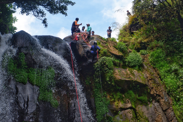 Para remaja ini menuruni tebing bebatuan dan meluncur di atas derasnya aliran air terjun menggunakan teknik yang biasa diterapkan dalam olahraga canyoning.