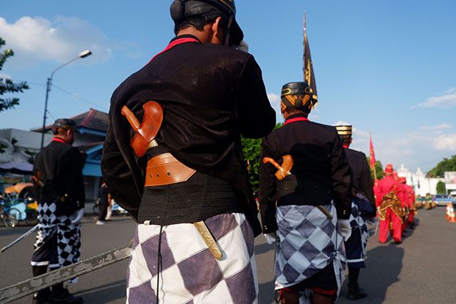Mereka membawa senjata khas seperti tombak dan keris serta berbaris mengikuti irama musik tambur dan terompet.