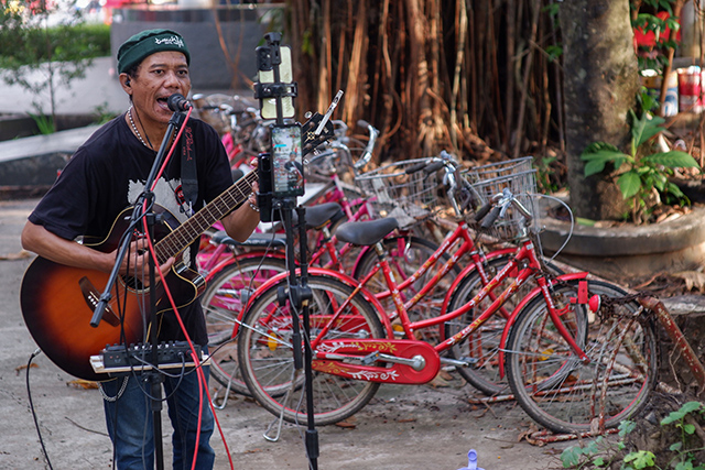 Seorang pengamen jalanan di Kota Makassar tampil penuh semangat di depan kamera ponsel untuk siaran langsung di TikTok.