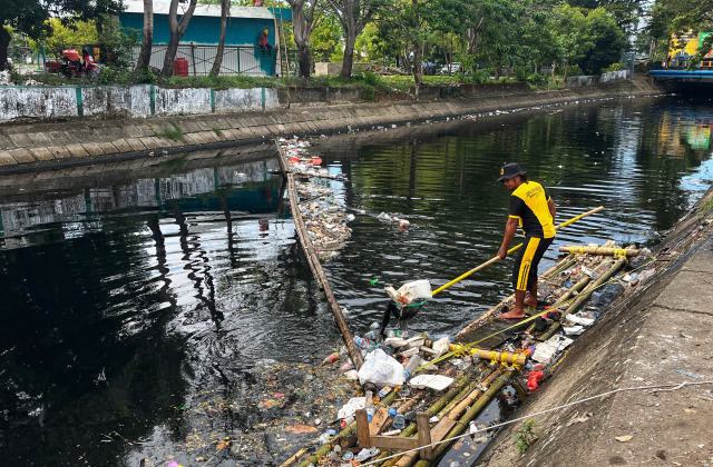 Satgas Kanal Dinas Pekerjaan Umum (PU) Kota Makassar membersihkan tumpukan sampah menggunakan jaring dari atas rakit bambu di Kanal Al-Markaz, Makassar, Rabu (9/7/2025).