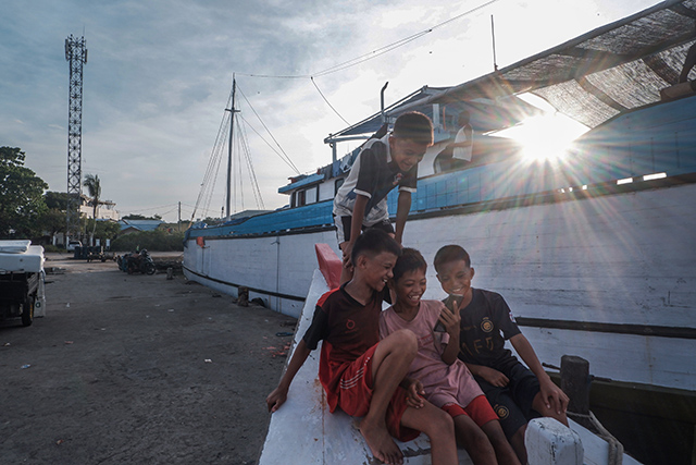 Anak-anak bermain ceria di atas buritan kapal kayu yang bersandar di Pelabuhan Paotere, Makassar.