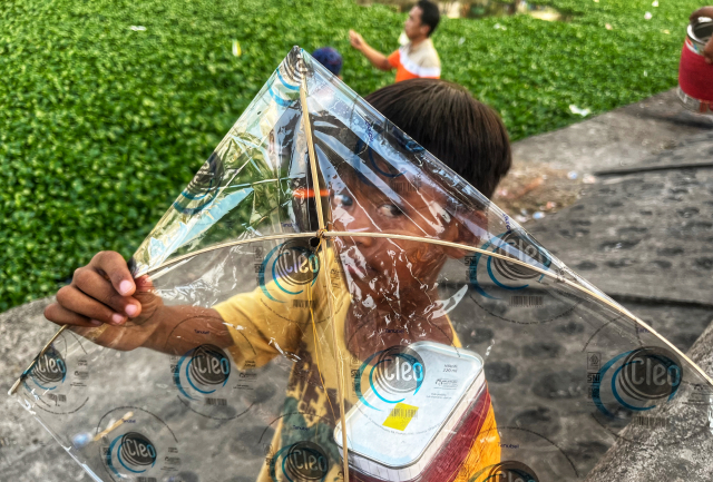 Seorang anak meperlihatkan layangannya saat bermain di bantaran kanal Batua, Kelurahan Borong, Makassar.