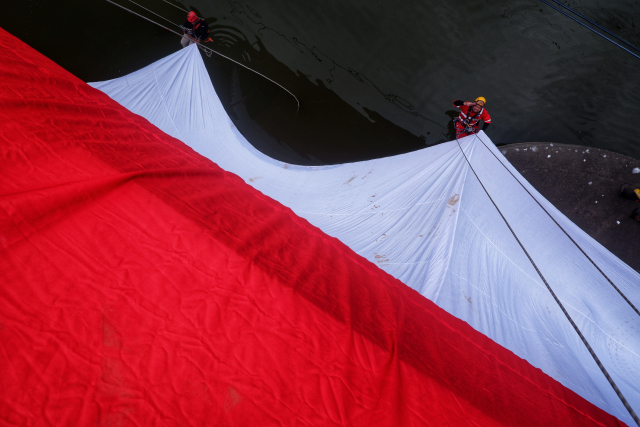 Sejumlah peserta melakukan pembentangan Bendera Merah Putih raksasa di Jembatan Kembar Sungguminasa.