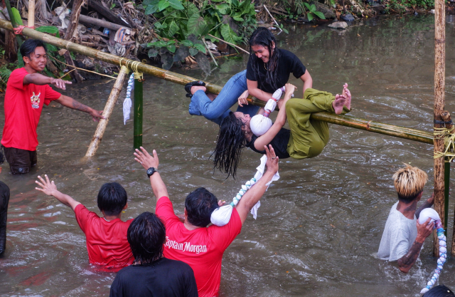 Tawa riuh penonton pecah setiap kali peserta terjatuh ke air, menambah kemeriahan suasana.