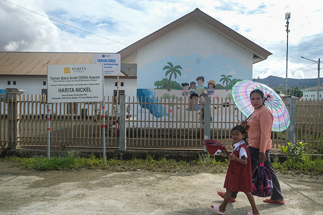Seorang ibu bersama anaknya melintas di depan Taman Baca Anak Ceria Kawasi, Pulau Obi, Maluku Utara, (17/9/2025). Sebanyak 259 unit rumah dibangun oleh Harita Nickel dengan berbagai tipe sesuai kebutuhan warga, dilengkapi sarana fasilitas umum termasuk gedung sekolah.
