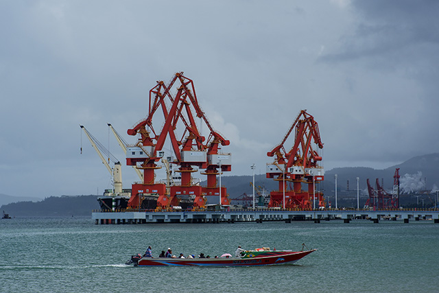 Perahu warga melintas di perairan sekitar pelabuhan industri Harita Nickel, Pulau Obi, Maluku Utara, yang dilengkapi fasilitas bongkar muat untuk mendukung hilirisasi nikel.