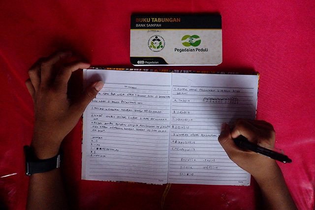 M. Izzan Syahmi, siswa SMP Negeri 27 Makassar, saat belajar di kelas. Di atas mejanya terlihat buku tabungan Bank Sampah hasil kerja sama sekolah dengan PT Pegadaian.