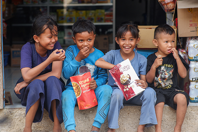 Anak-anak di Dusun Kuri Caddi, Desa Nisombalia, Kecamatan Marusu, Kabupaten Maros, Sulawesi Selatan, menikmati camilan keripik rajungan dan keripik ikan produksi kelompok UMKM Moms Keren, Sabtu (18/10/2025).