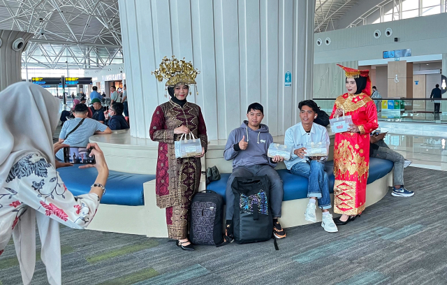 Sejumlah pegawai berpakaian adat dari berbagai daerah membagikan bingkisan kepada calon penumpang di Bandara Internasional Sultan Hasanuddin.