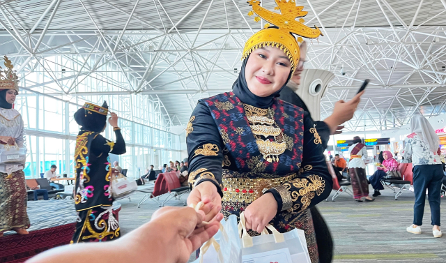 Sejumlah pegawai berpakaian adat dari berbagai daerah membagikan bingkisan kepada calon penumpang di Bandara Internasional Sultan Hasanuddin.
