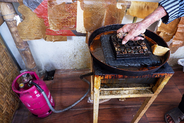 Tangan terampil seorang perajin batik mencelupkan cap tembaga ke dalam cairan lilin panas yang dipanaskan menggunakan Bright Gas Pertamina di salah satu bengkel Batik Gunasti, Kampung Batik Kauman, Solo.