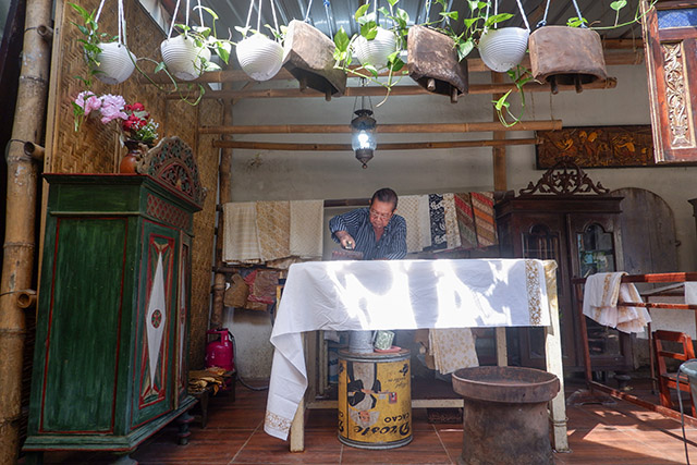 Sukadi, perajin batik dari Batik Gunasti di Kampung Batik Kauman, Solo, dengan telaten mencetak motif batik cap di atas kain putih di ruang kerjanya yang sederhana.