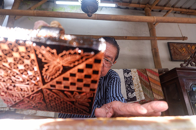 Sukadi, perajin batik dari Batik Gunasti, Kampung Batik Kauman, Solo, dengan teliti menekan cap tembaga bermotif klasik yang telah dicelupkan ke lilin panas ke atas kain mori.  foto 7.