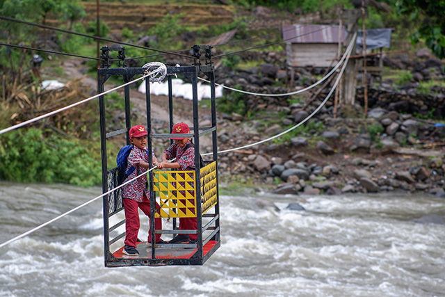 Dua siswa sekolah dasar menyeberangi Sungai Tompobulu dengan menggunakan gondola di Dusun Makmur, Desa Bonto Manurung, Kabupaten Maros.