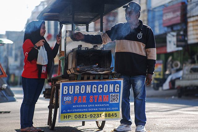 Syam, pedagang kue buroncong di Makassar, melayani pembayaran pelanggan menggunakan QRIS BRI pada Minggu (16/11/2025).