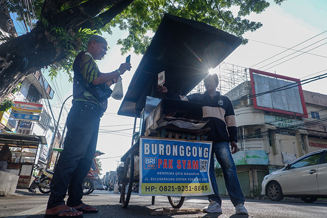 Syam, pedagang kue buroncong di Makassar, melayani pembayaran pelanggan menggunakan QRIS BRI pada Minggu (16/11/2025).
