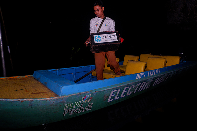 Sunardi membawa baterai perahu listrik bantuan PLN untuk diisi ulang di rumahnya di Desa Berua, Rammang-Rammang, Maros. Pengisian rutin memastikan perahu siap digunakan setiap hari untuk aktivitas warga dan transportasi pelajar.