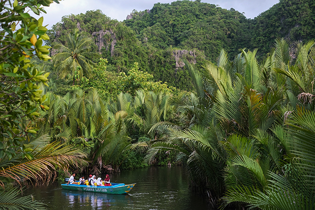 Perahu listrik bantuan PLN mengantar anak-anak sekolah melintasi sungai di tengah rimbunnya kawasan karst Rammang-Rammang, menjadi transportasi ramah lingkungan yang kini diandalkan warga Desa Berua.