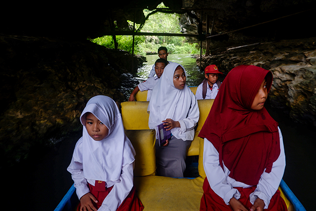 Beberapa anak-anak sekolah tampak menikmati perahu listrik yang mengantarnya ke sekolah melintasi sungai di Desa Berua, Rammang-Rammang.