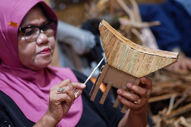 Seorang perajin Komunitas Pemberdayaan Kasih Bunda menganyam eceng gondok menjadi suvenir miniatur rumah Toraja di Makassar.