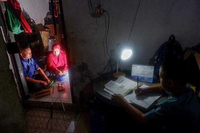 Hasbi Assidik belajar dengan tekun sementara kedua orang tuanya, Abdul Rahman dan Komaria, menyiapkan bahan masakan di rumah mereka di Kompleks Perumnas Antang, Makassar.