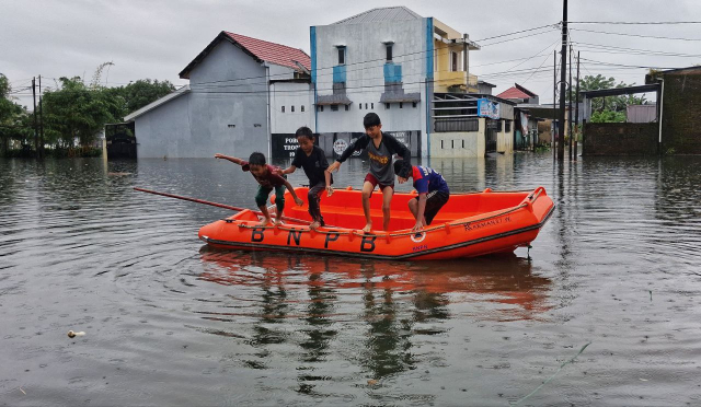 Sejumlah anak melompat dari perahu karet milik Badan Nasional Penanggulangan Bencana (BNPB) saat banjir merendam kawasan Blok 10 Perumnas Antang, Makassar.