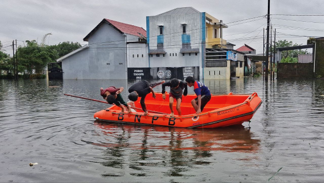 Sejumlah anak melompat dari perahu karet milik Badan Nasional Penanggulangan Bencana (BNPB) saat banjir merendam kawasan Blok 10 Perumnas Antang, Makassar.