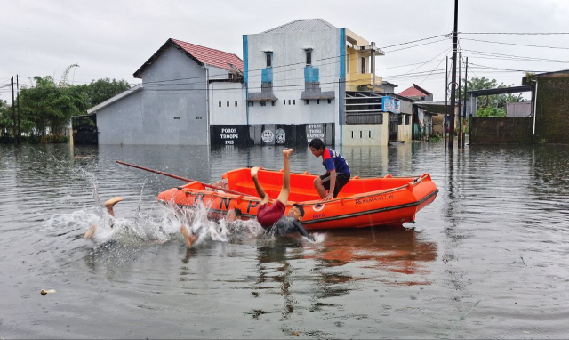 Sejumlah anak melompat dari perahu karet milik Badan Nasional Penanggulangan Bencana (BNPB) saat banjir merendam kawasan Blok 10 Perumnas Antang, Makassar.