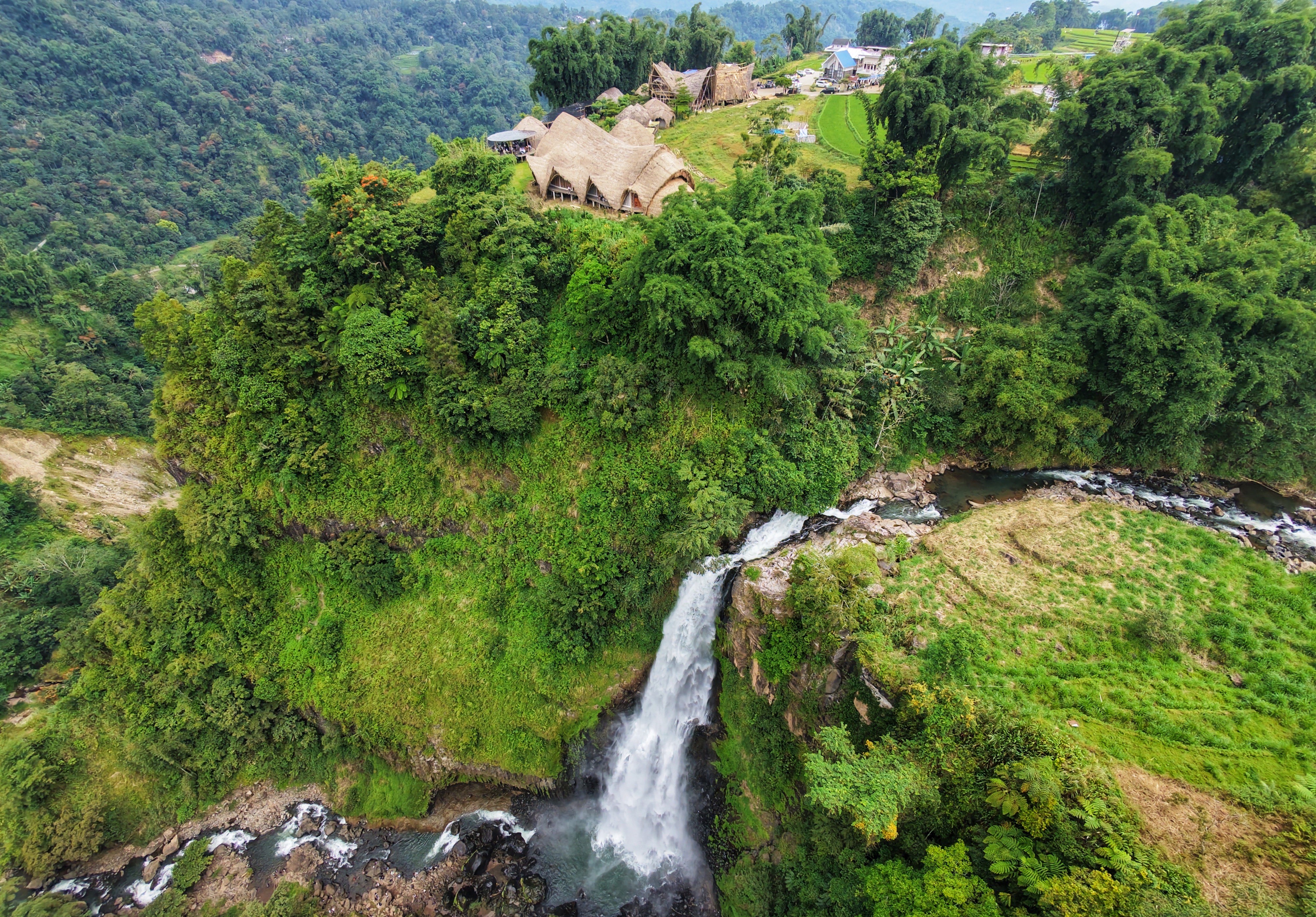 Debit air yang deras mengalir dari tebing curam, berpadu dengan hamparan hijau hutan tropis yang masih asri, menciptakan panorama alam yang menenangkan sekaligus menyegarkan pandangan.