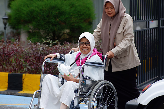Seorang petugas mendampingi jamaah calon haji lanjut usia menggunakan kursi roda di kawasan Asrama Haji Makassar.