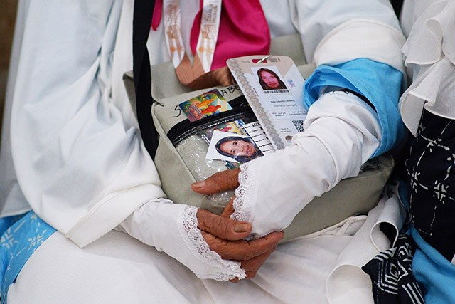 Seorang jamaah calon haji menggenggam dokumen perjalanan yang berisi paspor dan identitas diri di Asrama Haji Makassar.