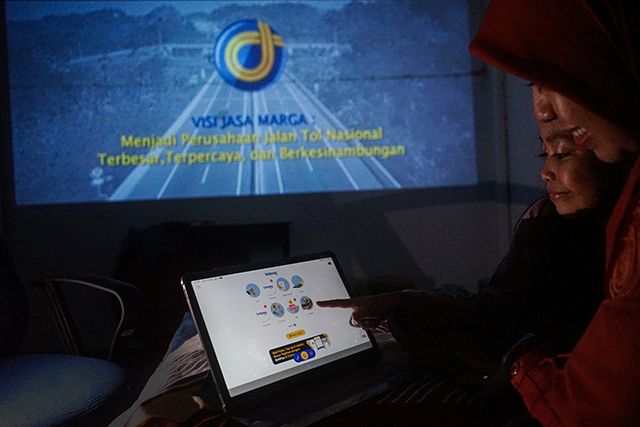 Seorang warga bersama anaknya mengakses aplikasi Travoy melalui perangkat tablet di rumahnya di Makassar, (15/3/2026). Aplikasi ini menjadi bagian dari inovasi digital Jasa Marga dalam memberikan layanan informasi perjalanan tol secara praktis dan real-time kepada pengguna.