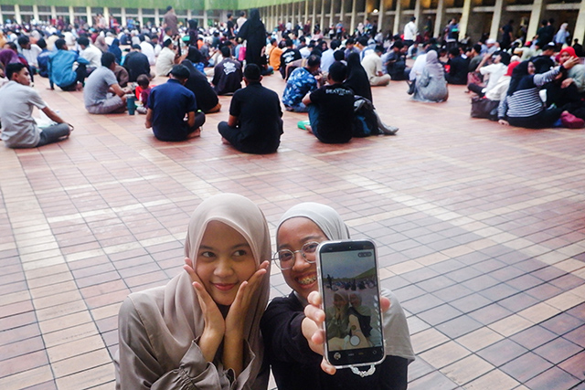 Dua orang jamaah perempuan berswafoto bersama di tengah ribuan warga yang memadati pelataran Masjid Istiqlal, Jakarta, menjelang waktu berbuka puasa.