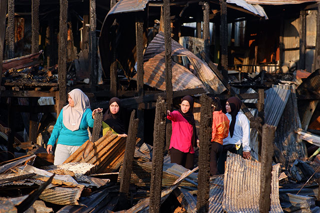 Sejumlah warga melintasi puing-puing rumah yang hangus terbakar di Kampung Mangarabombang, Kecamatan Tallo, Makassar, Sulawesi Selatan, Jumat (31/7/2026).