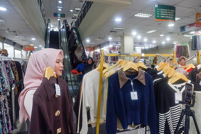Seorang pedagang pakaian memasarkan produknya secara daring melalui platform Shopee di Pasar Tanah Abang, Jakarta Pusat, Sabtu (28/2/2026).