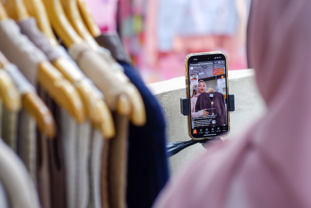 Seorang pedagang pakaian memasarkan produknya secara daring melalui platform Shopee di Pasar Tanah Abang, Jakarta Pusat, Sabtu (28/2/2026).