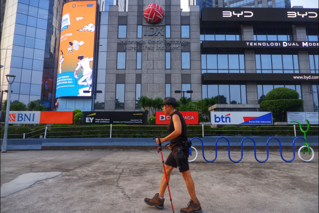 Seorang pejalan kaki menggunakan tongkat berjalan melintas di depan gedung Bursa Efek Indonesia (BEI), Jakarta.