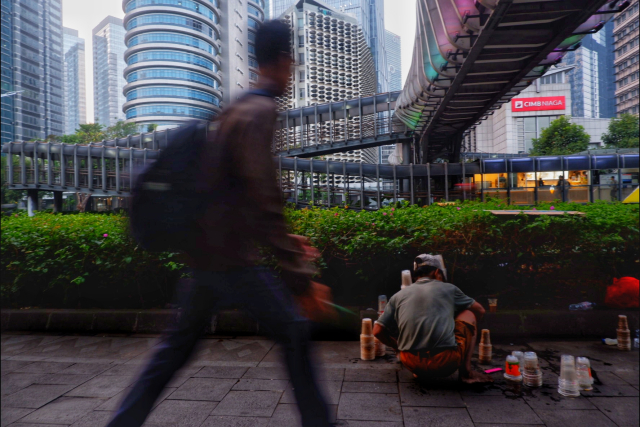 Seorang pekerja berjalan melintas di depan pedagang minuman yang tengah berjualan di kawasan pusat bisnis Jakarta