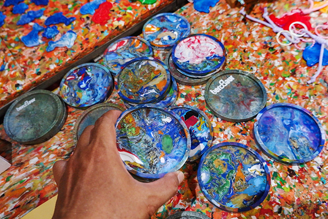 Seorang pengunjung memegang produk berbentuk tatakan hasil olahan limbah plastik yang dibuat dengan perpaduan warna dan motif menyerupai lukisan dalam Festival Mindspace Chapter III bertema Artistic Ecology di Makassar, Sulawesi Selatan, Minggu (25/10/2026).